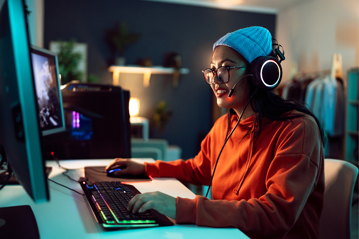 Woman with headphones sitting at a gaming PC